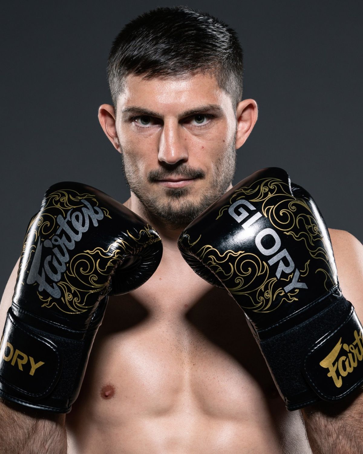Boxer holding black and gold Fairtex boxing gloves